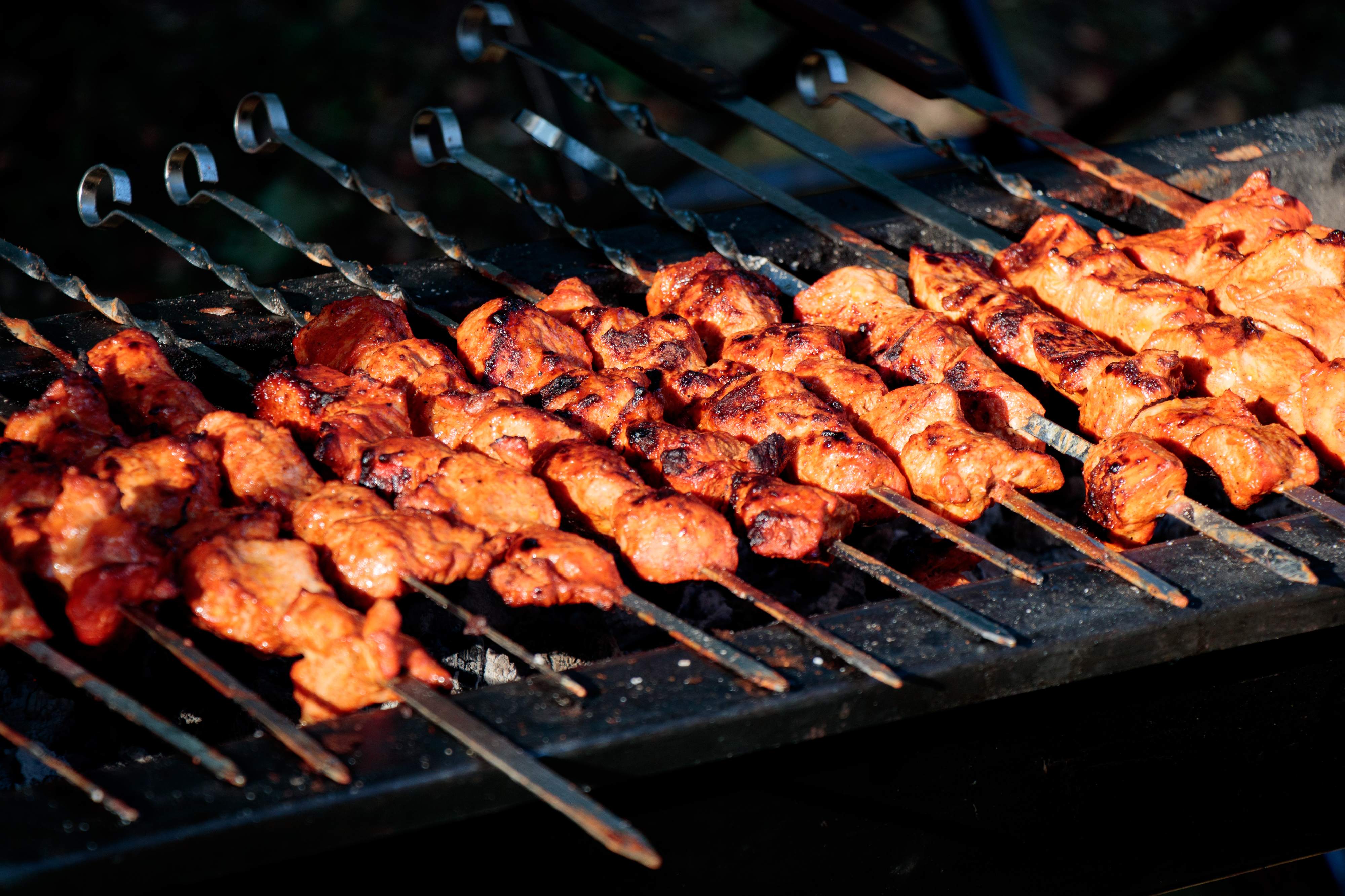 Rows of marinated chicken tikka grilling over charcoal
